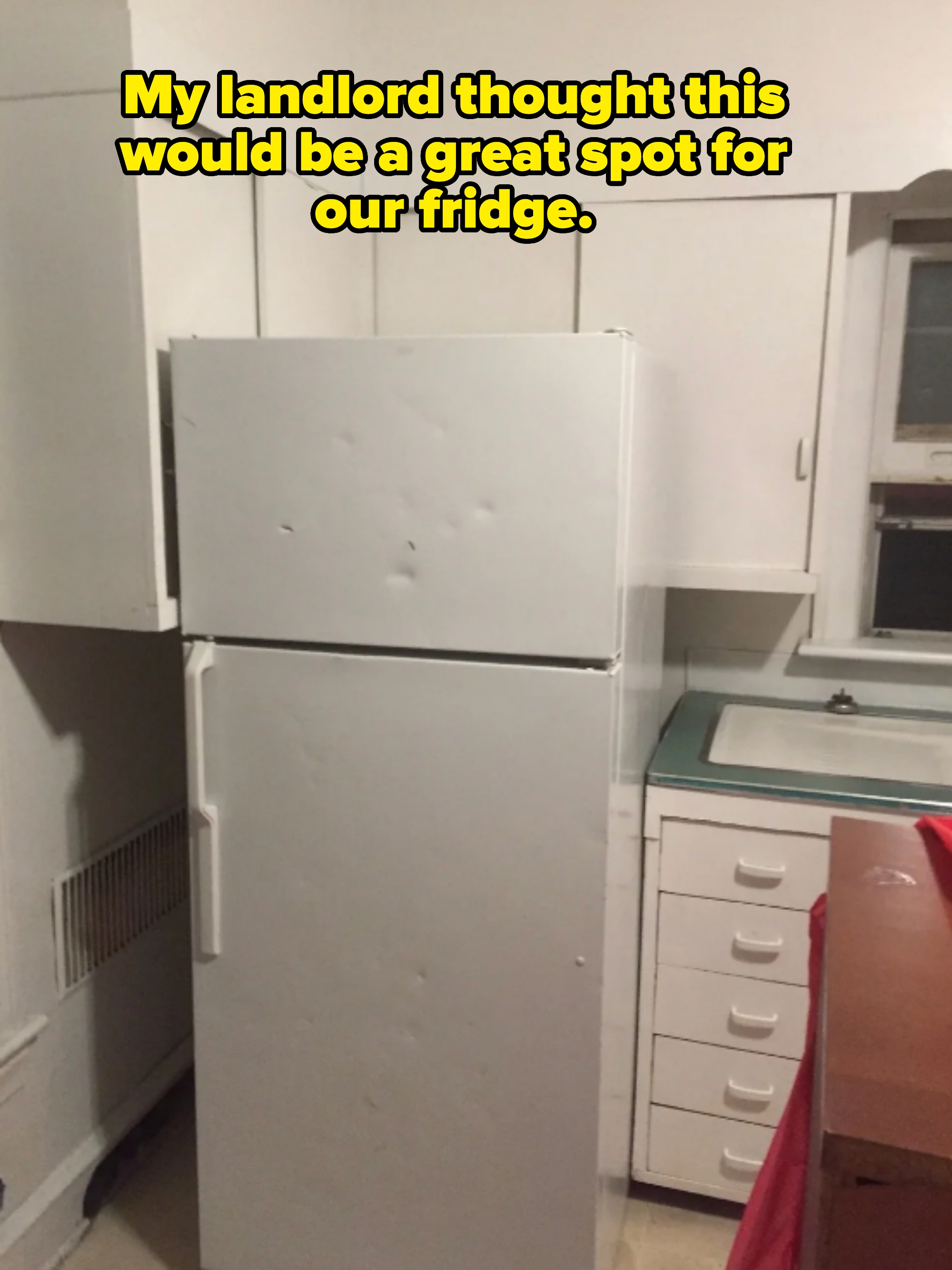 A kitchen with a refrigerator blocking all the cabinets captioned "My landlord thought this would be a great spot for our fridge"