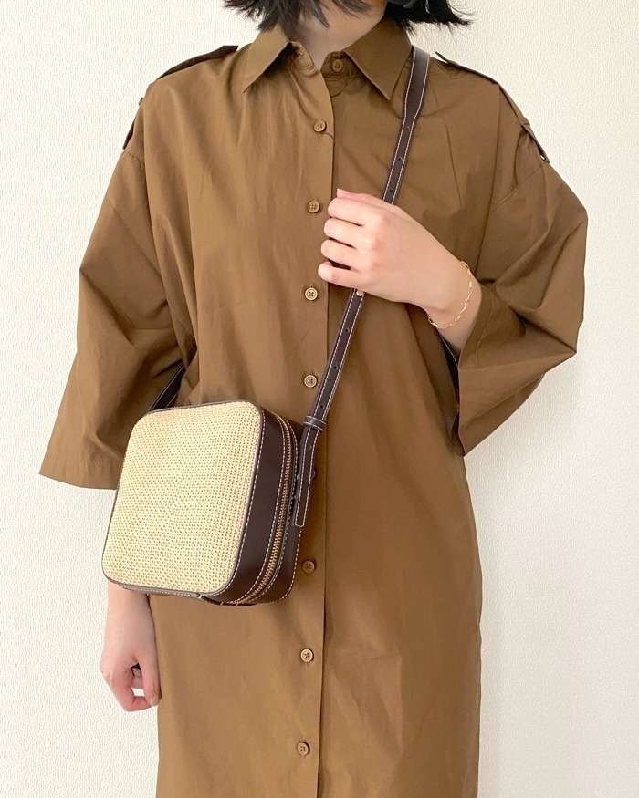 シャツドレスを着た人物が肩に四角いバッグをかけている。シンプルで落ち着いたデザインのファッション。