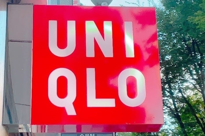 ユニクロの看板が外壁に掛かっている。背景に木々が見える。