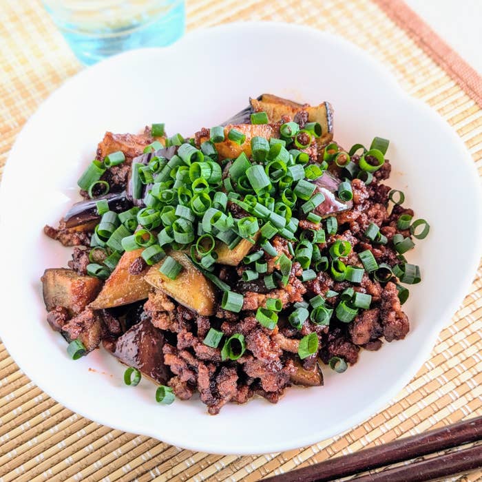 器に盛られたひき肉となすの炒め物に、小ネギがたっぷりと振りかけられている。