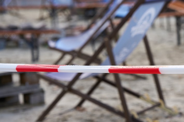 ビーチに設置されたスマートなデッキチェアが見え、手前には立ち入り禁止を示すテープが張られています。