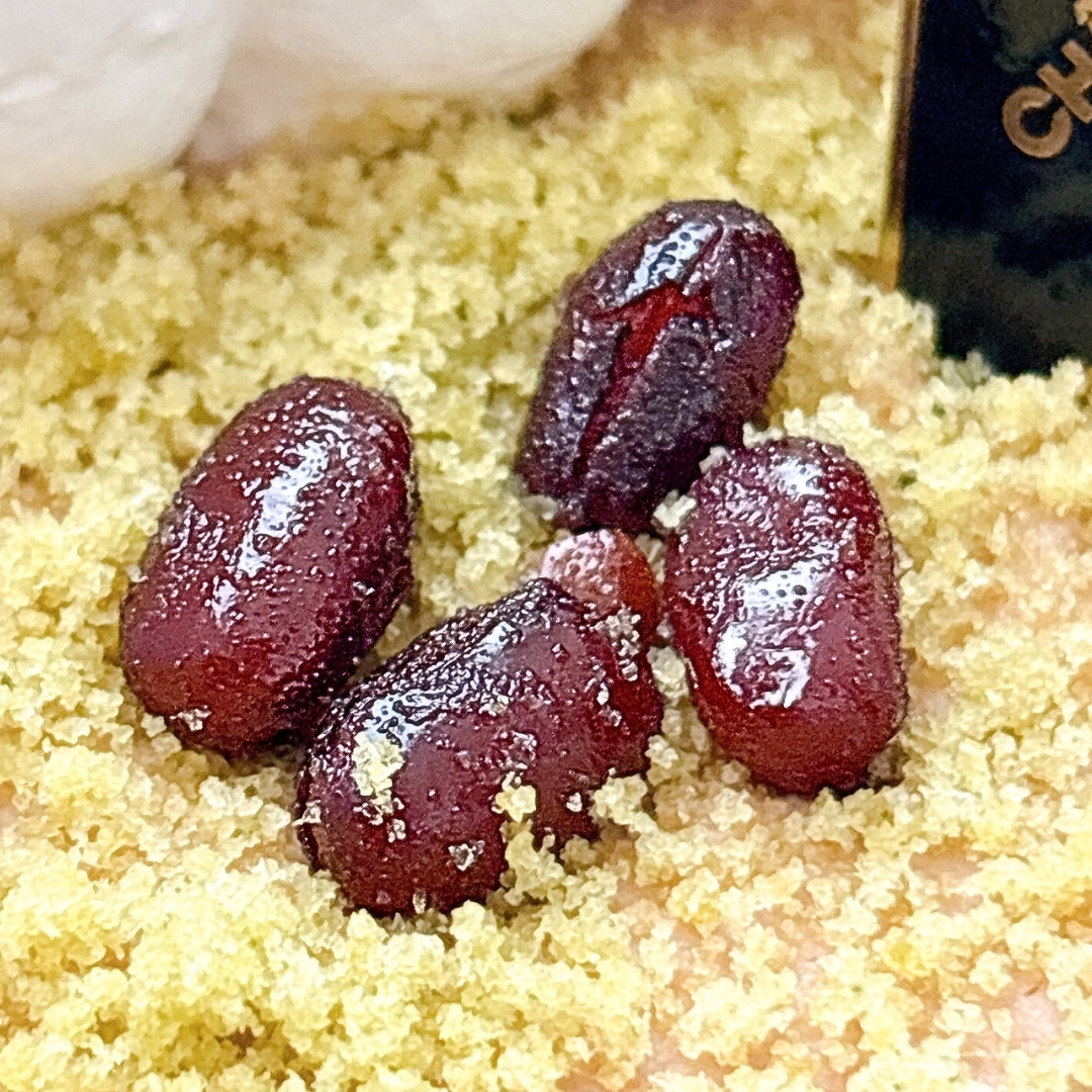 黄色い粉の上に、糖がかかった赤い干しブドウが複数載っている。