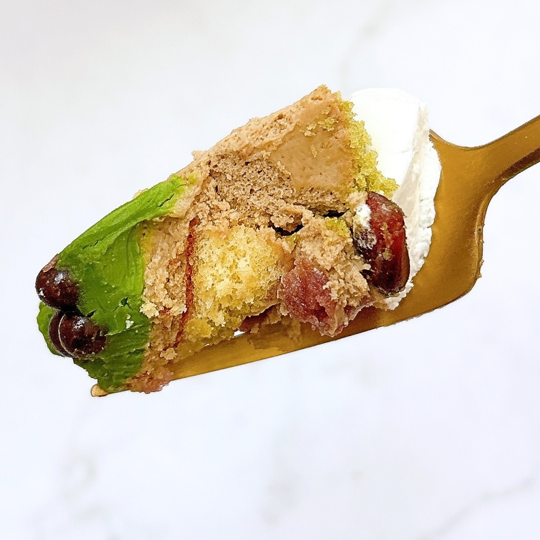 クリームたっぷりのケーキの一切れをスプーンですくった様子。飾られた豆が見える。