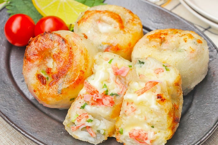 お皿に盛られたカニクリームチーズ入りのもちもちポテトボール。トマトとレモンが添えられ、飲み物が後ろに見える。