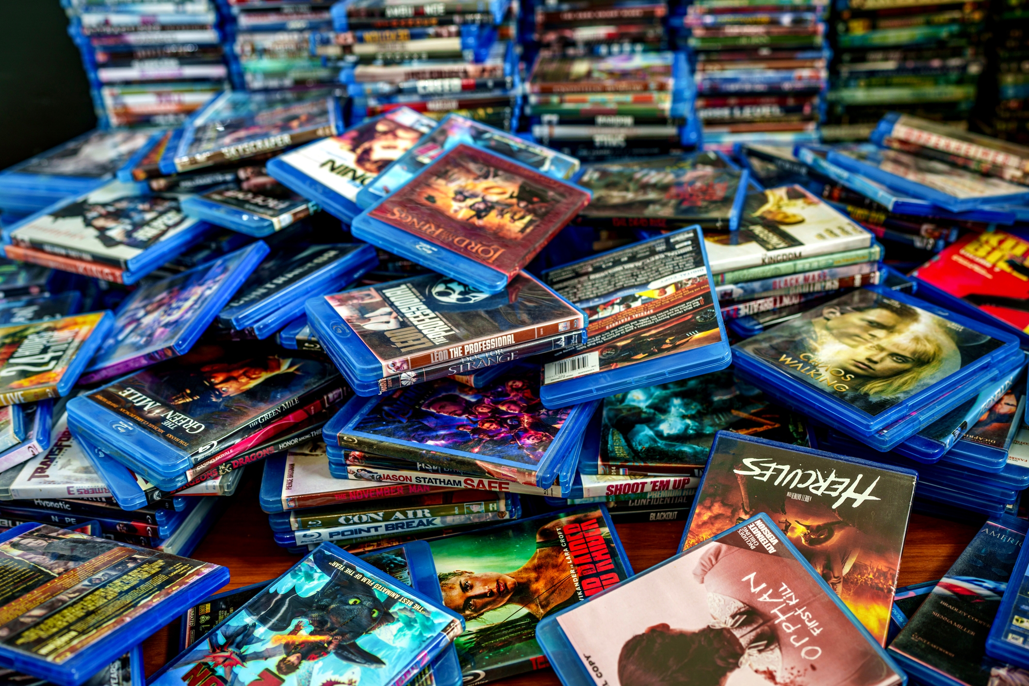 Stacks of various Blu-ray movie cases are scattered, showcasing a mix of genres and titles