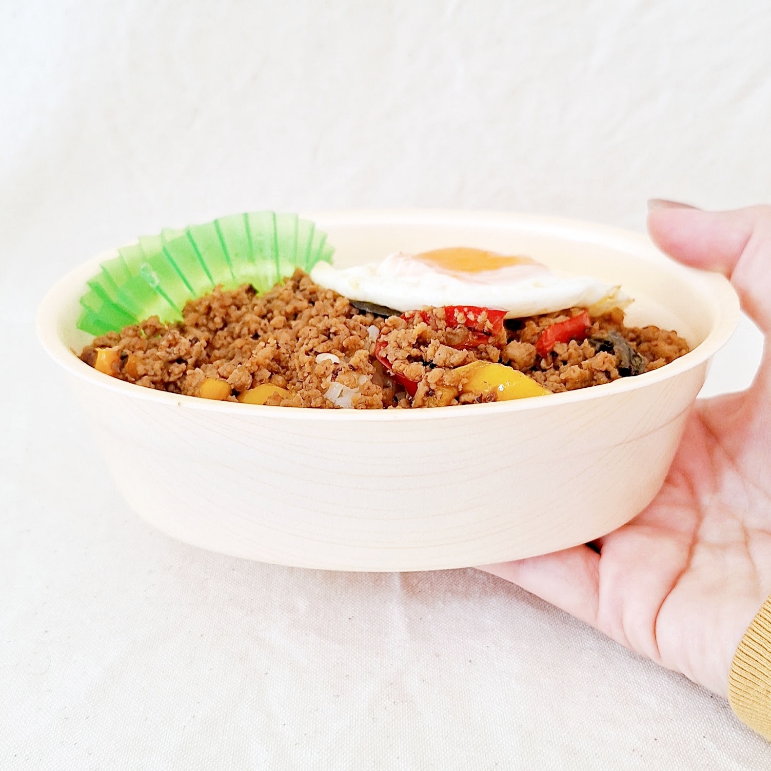 皿に盛られたそぼろご飯と目玉焼き、手に持たれている。