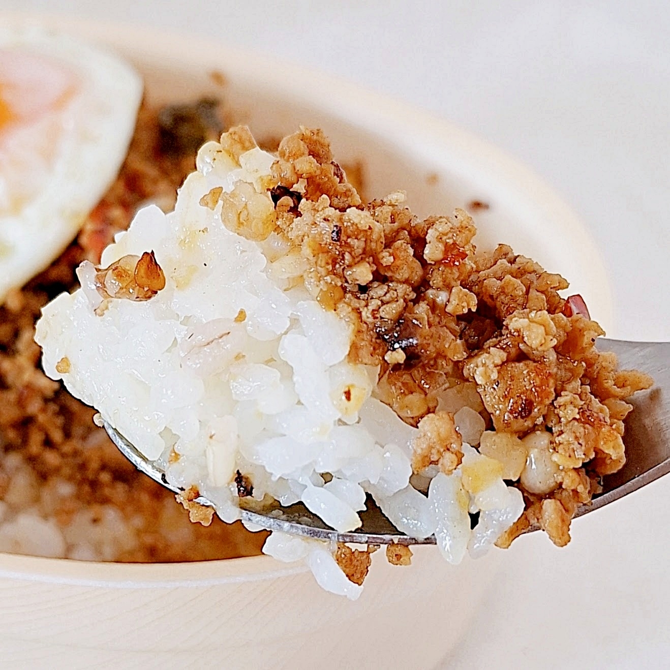 スプーンで持ち上げた白いご飯と肉そぼろ。