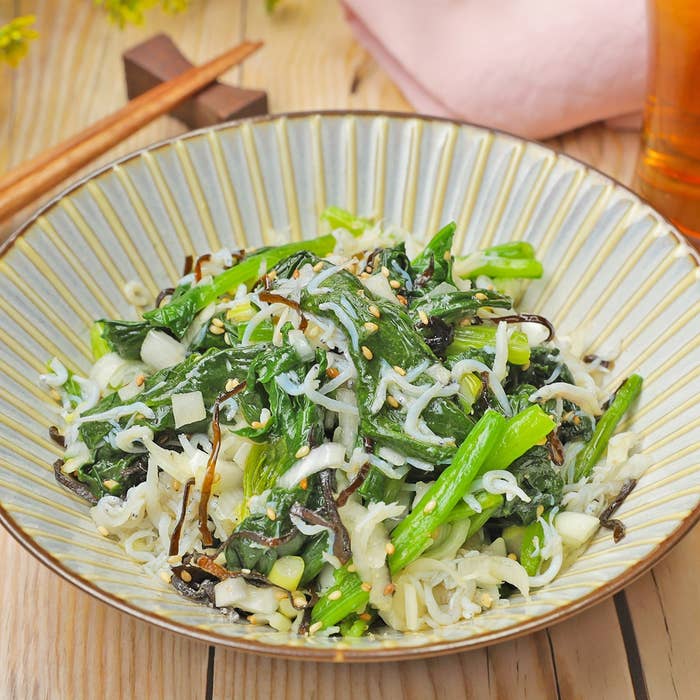 皿に盛られた青菜、ちりめんじゃこ、昆布とゴマの和風サラダ。食卓に箸が置かれている。