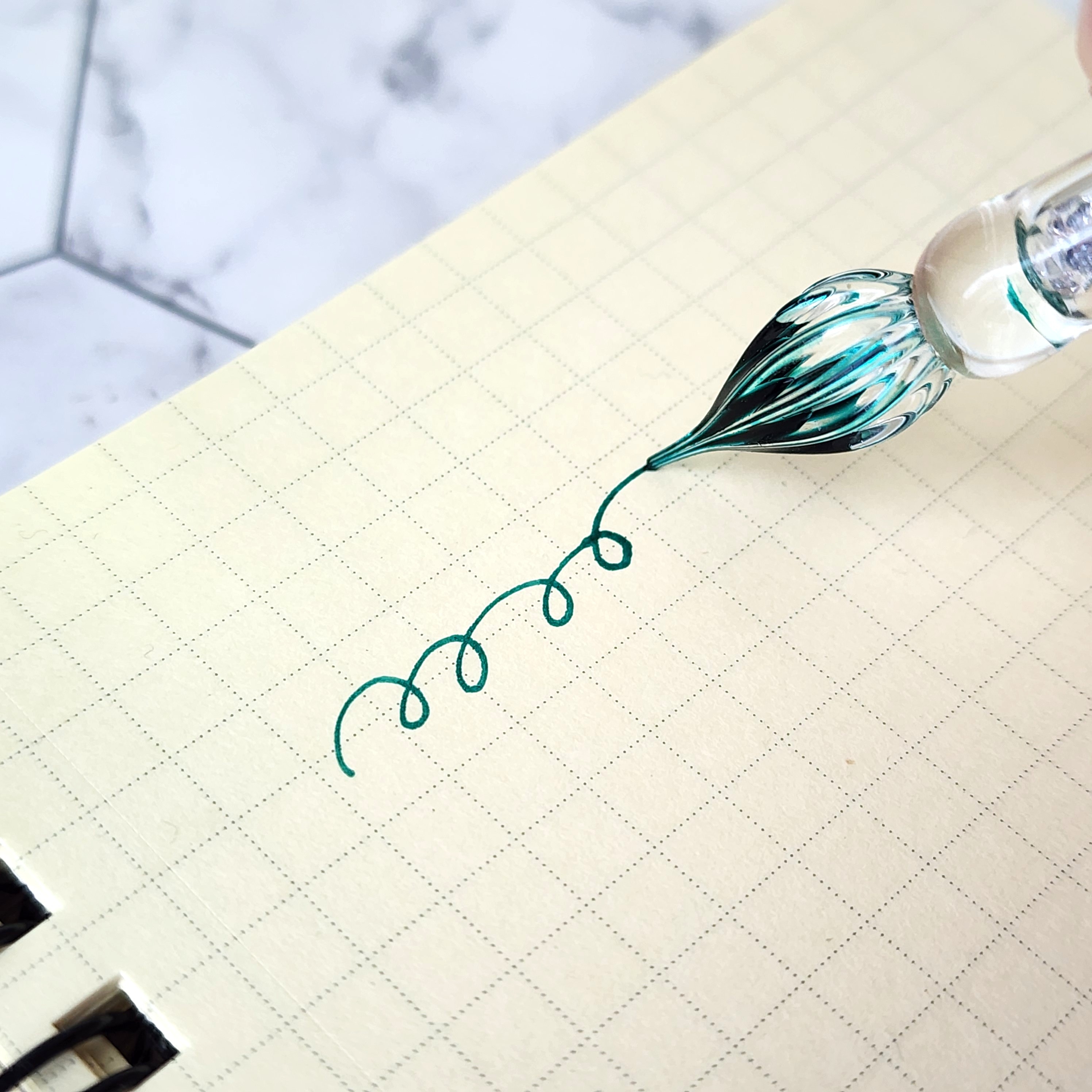 ノートにガラスペンで巻き線を描く様子。