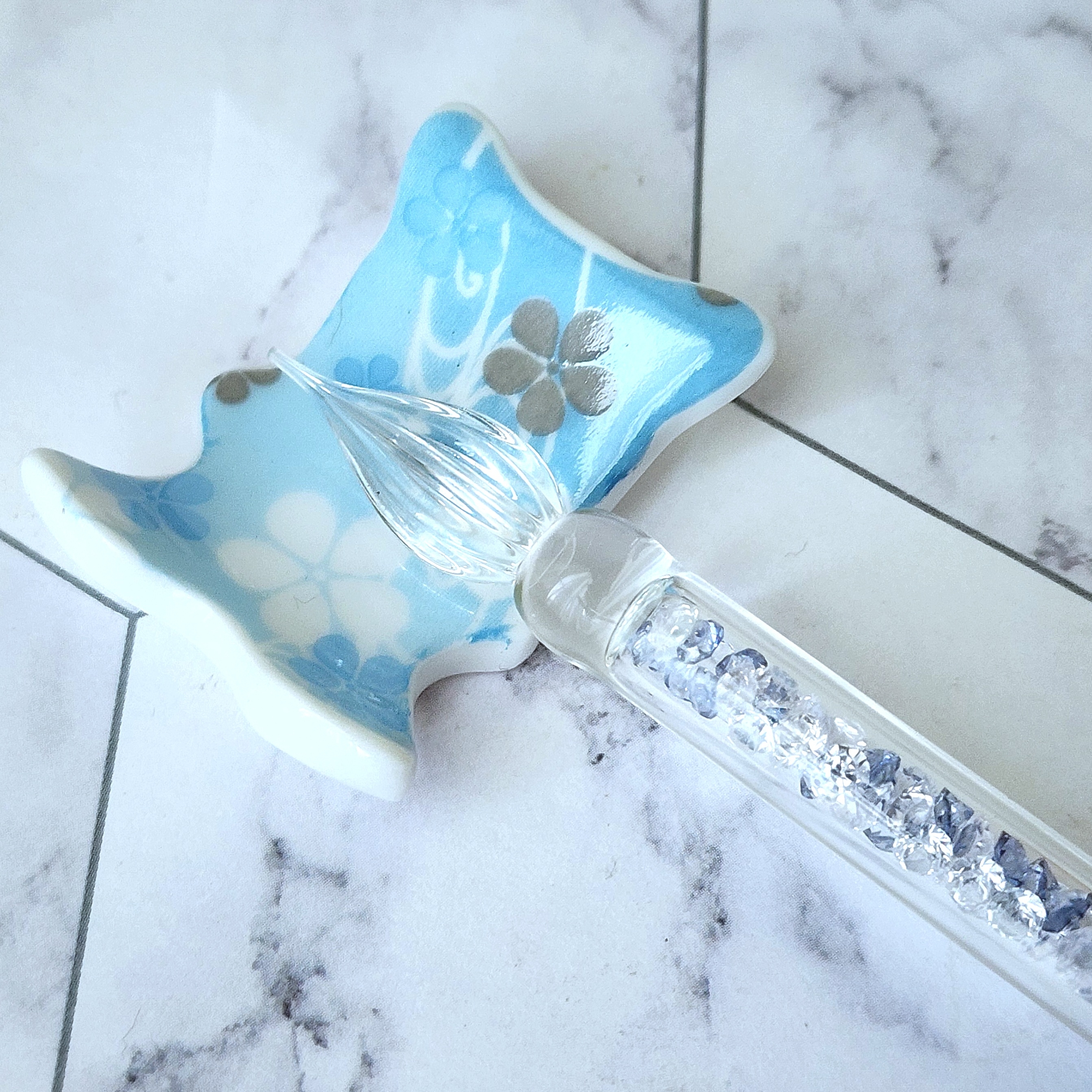 陶器の花柄の小皿と装飾が施されたガラスペンが並んでいる。