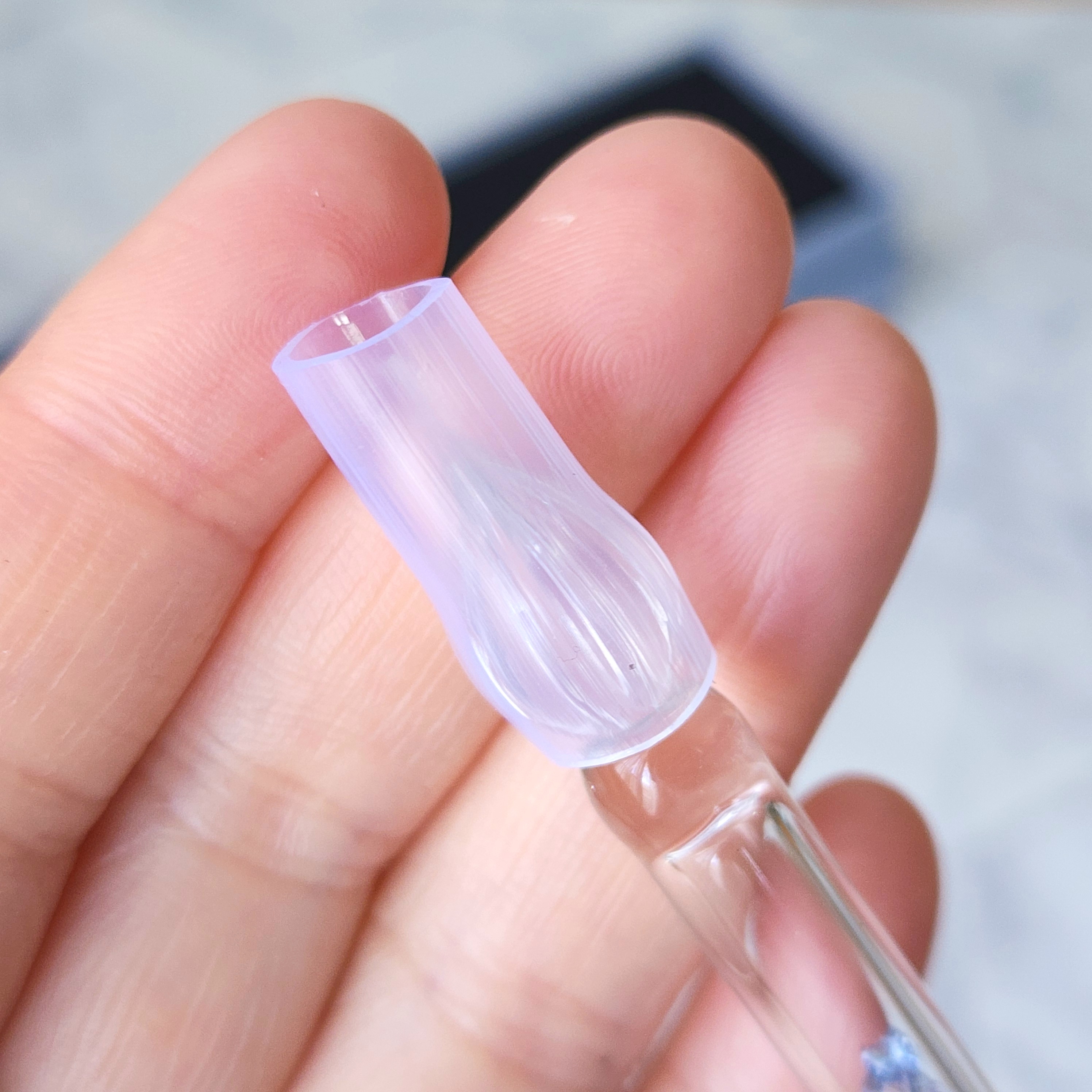 ガラス製のスポイトの先端を指でつまんでいる手元のクローズアップ。