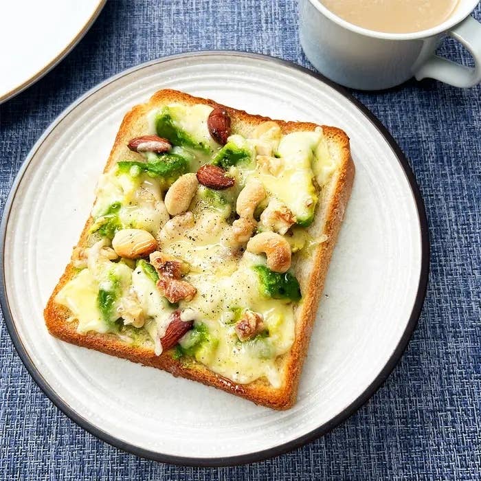 ナッツと緑のペーストがのったトーストとコーヒーカップがテーブルに置かれている。