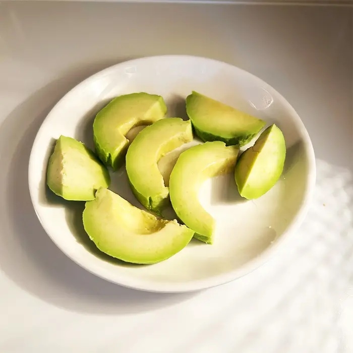 白い皿にアボカドのスライスが並べられている様子。