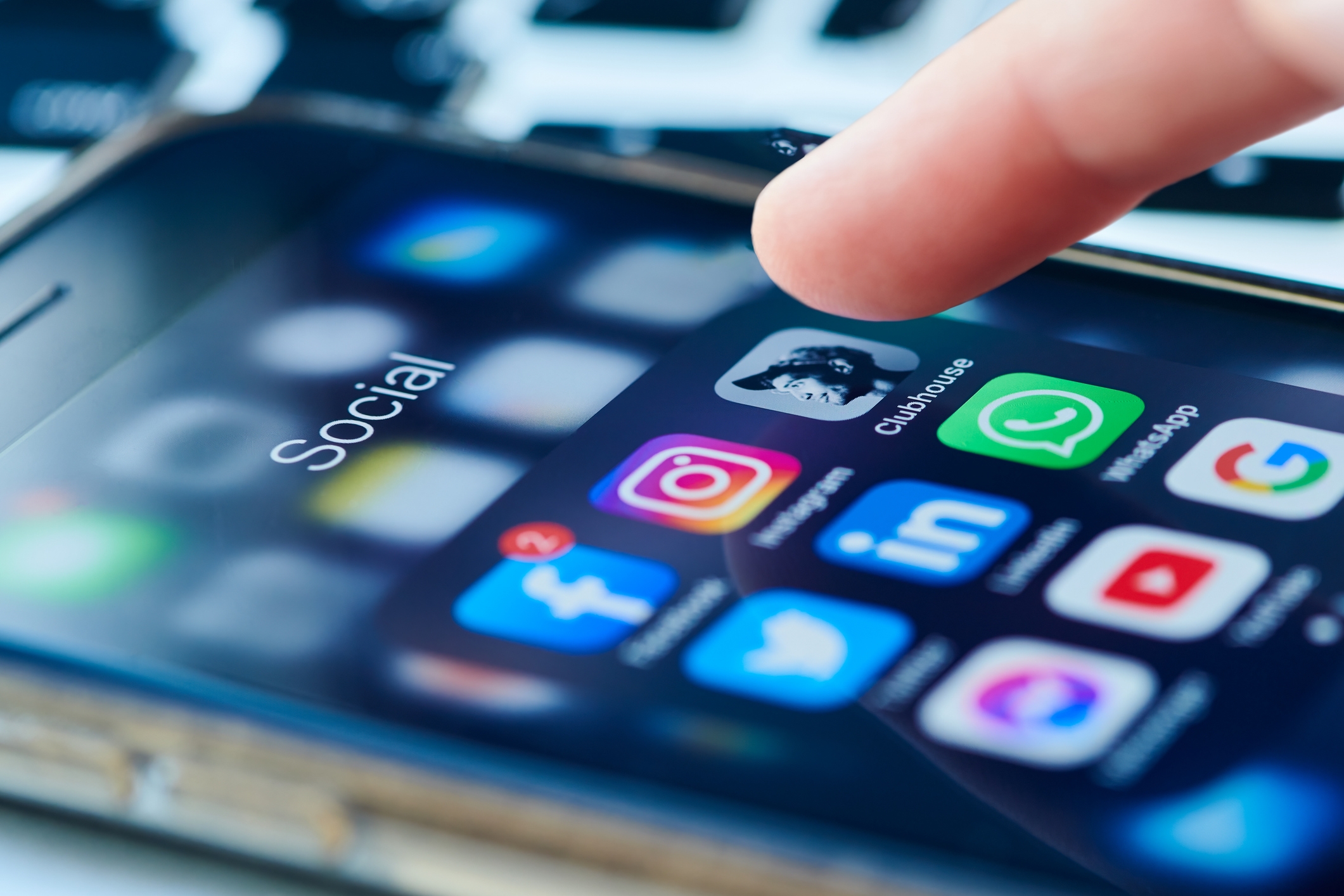En smarttelefonskjerm viser forskjellige appikoner for sosiale medier, inkludert Instagram, WhatsApp, LinkedIn og Clubhouse, mens en finger henger over dem