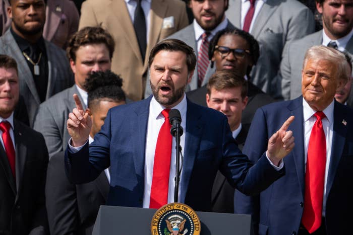 A man speaks passionately at a podium with the presidential seal, surrounded by a group of men in suits