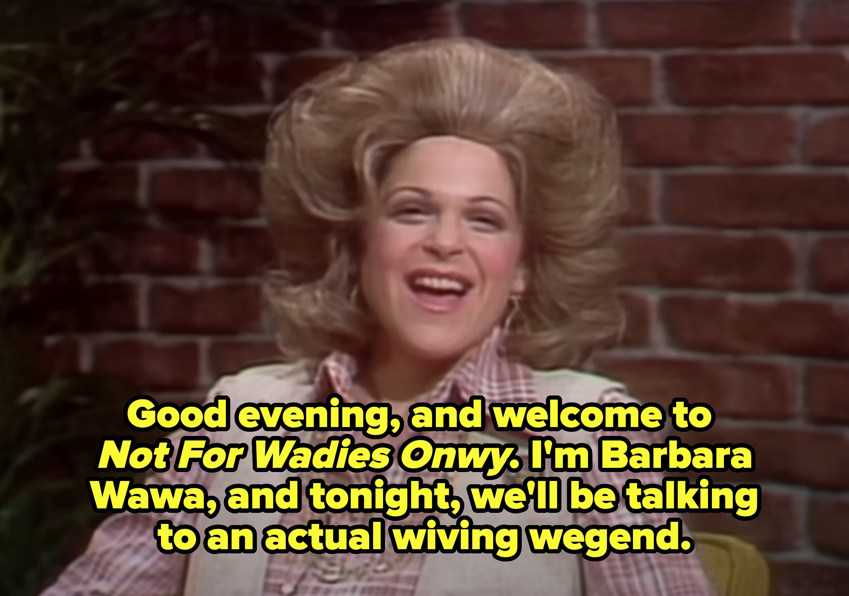 Gilda with voluminous, styled hair laughs. She says, "Good evening, and welcome to Not For Wadies Onwy. I'm Barbara Wawa, and tonight, we'll be talking to an actual wiving wegend"
