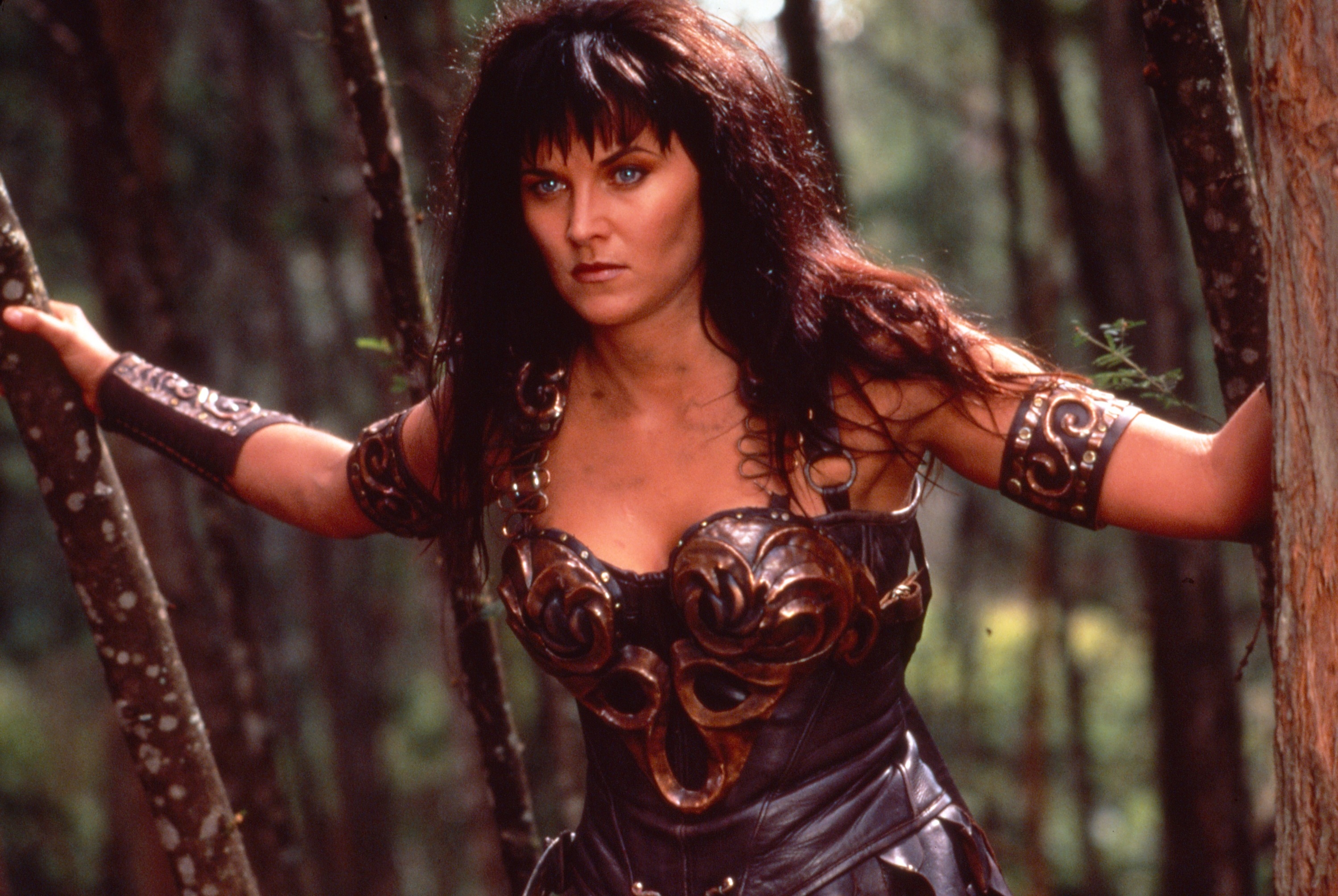 Person in warrior-style leather armor stands in a forest, looking focused and determined