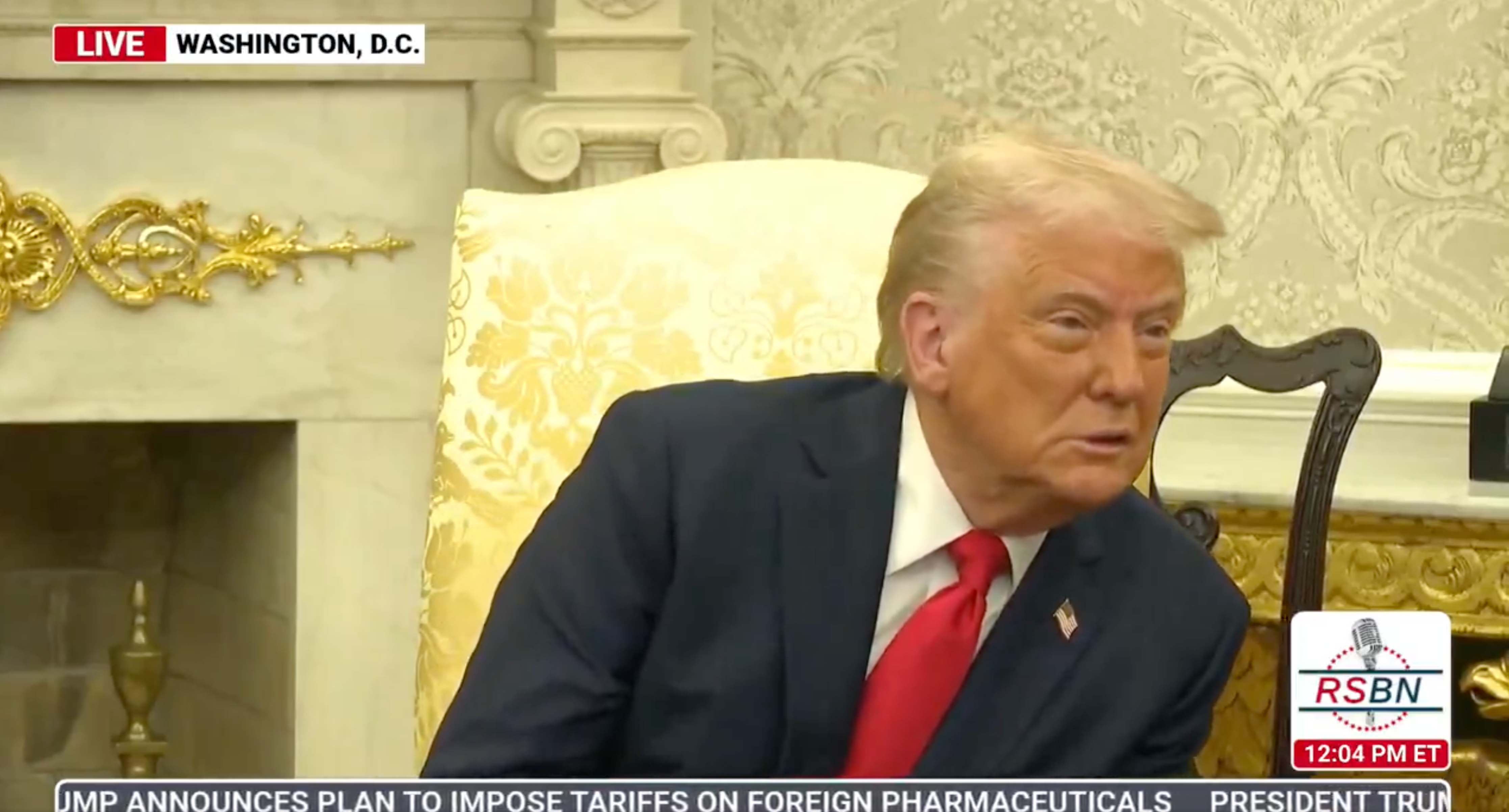 A man in a suit with a red tie is seated in a formal room in Washington, D.C., appearing engaged in conversation