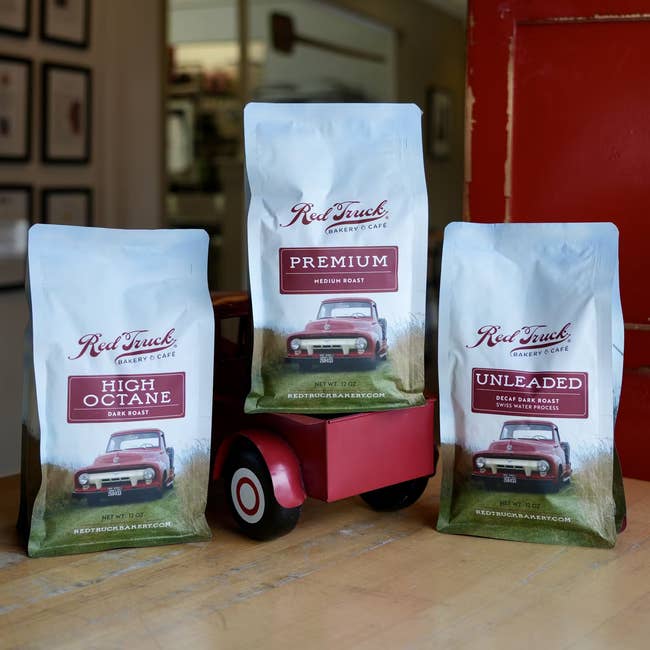 Three bags of full legume java from Red Truck Bakery successful High Octane, Premium, and Unleaded varieties, posed with a reddish artifact motortruck connected a woody surface