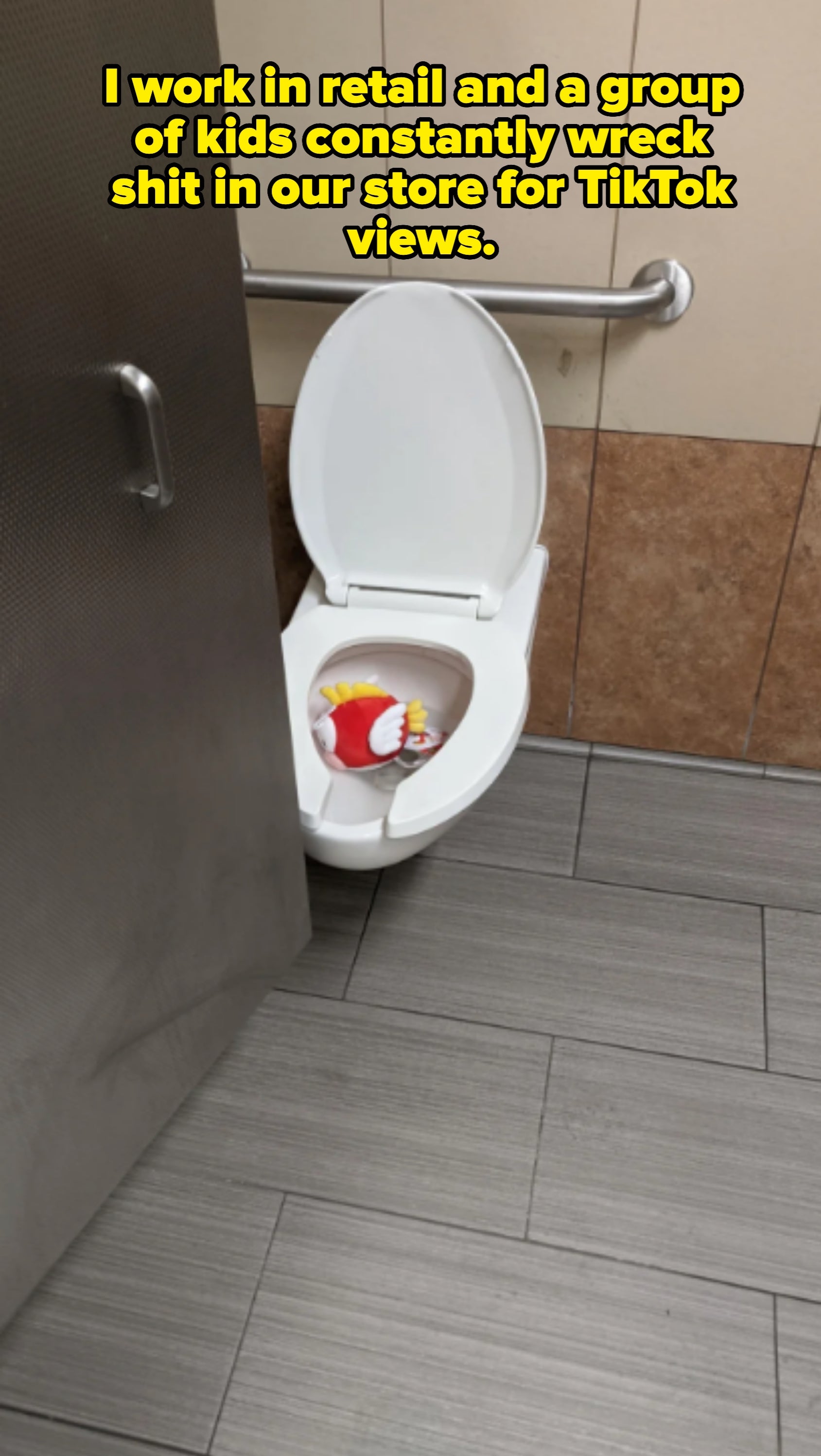 Toilet with open lid and McDonald's drink cup inside, in a tiled bathroom with a safety bar on the wall
