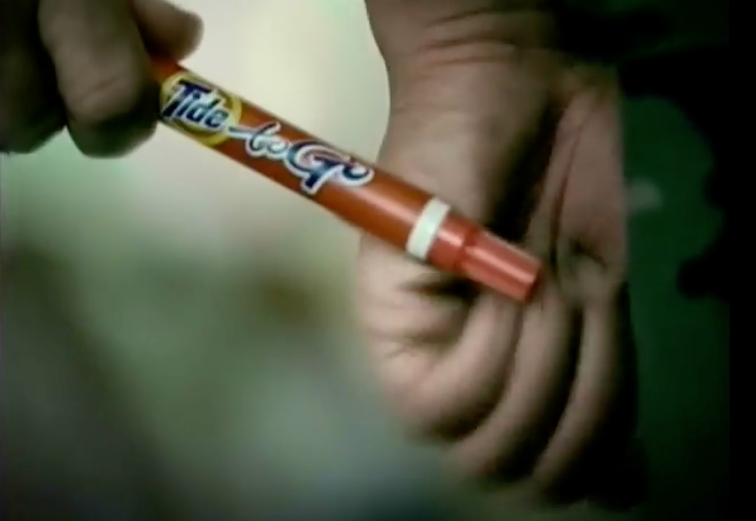 A hand holding a Tide To Go stain remover pen