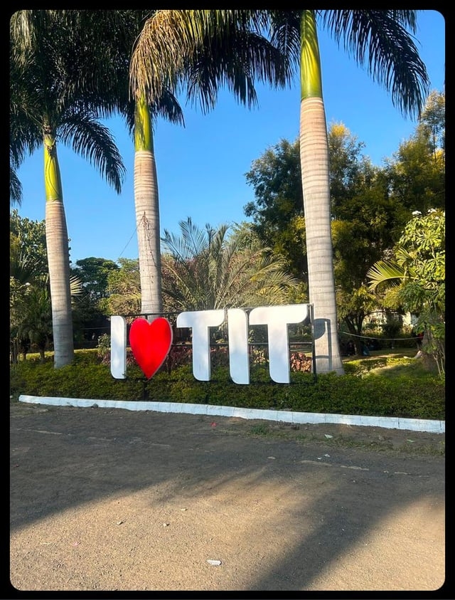 Large sign with palm trees in the background, reading “I ❤️ TIT.”