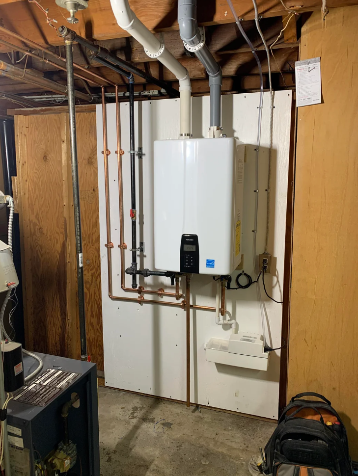 Image showing a Reddit post about a 4th-year apprentice seeking advice on tankless water heaters. The background is a plumbing setup in a basement