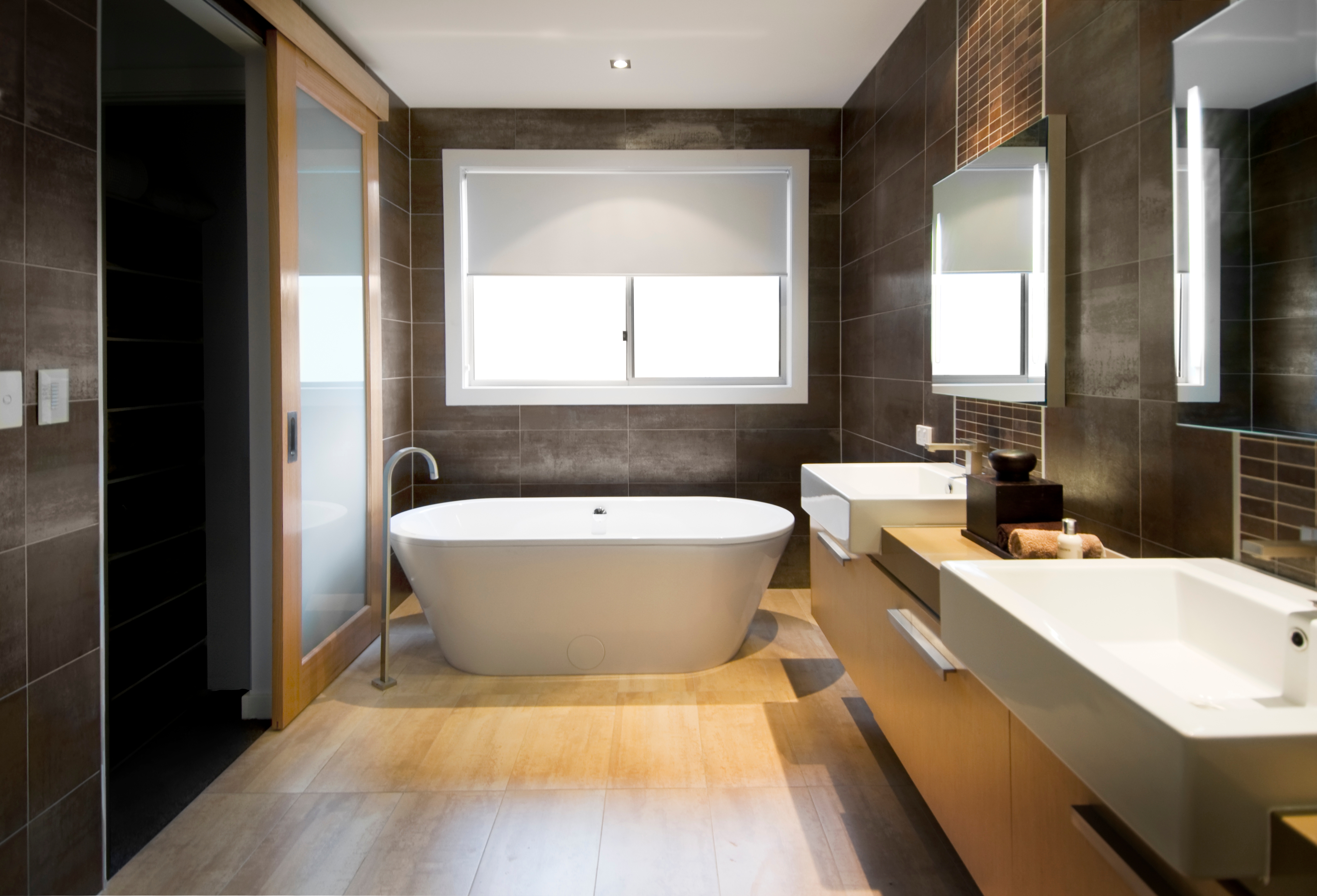 Modern bathroom featuring a central freestanding bathtub, double sinks, and large mirror, with sleek, minimalist design elements