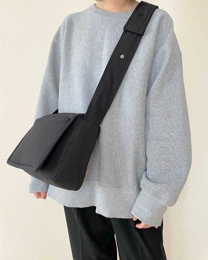 ゆったりしたトップスと斜め掛けバッグを身に着けた人物の上半身。リラックスしたカジュアルスタイル。