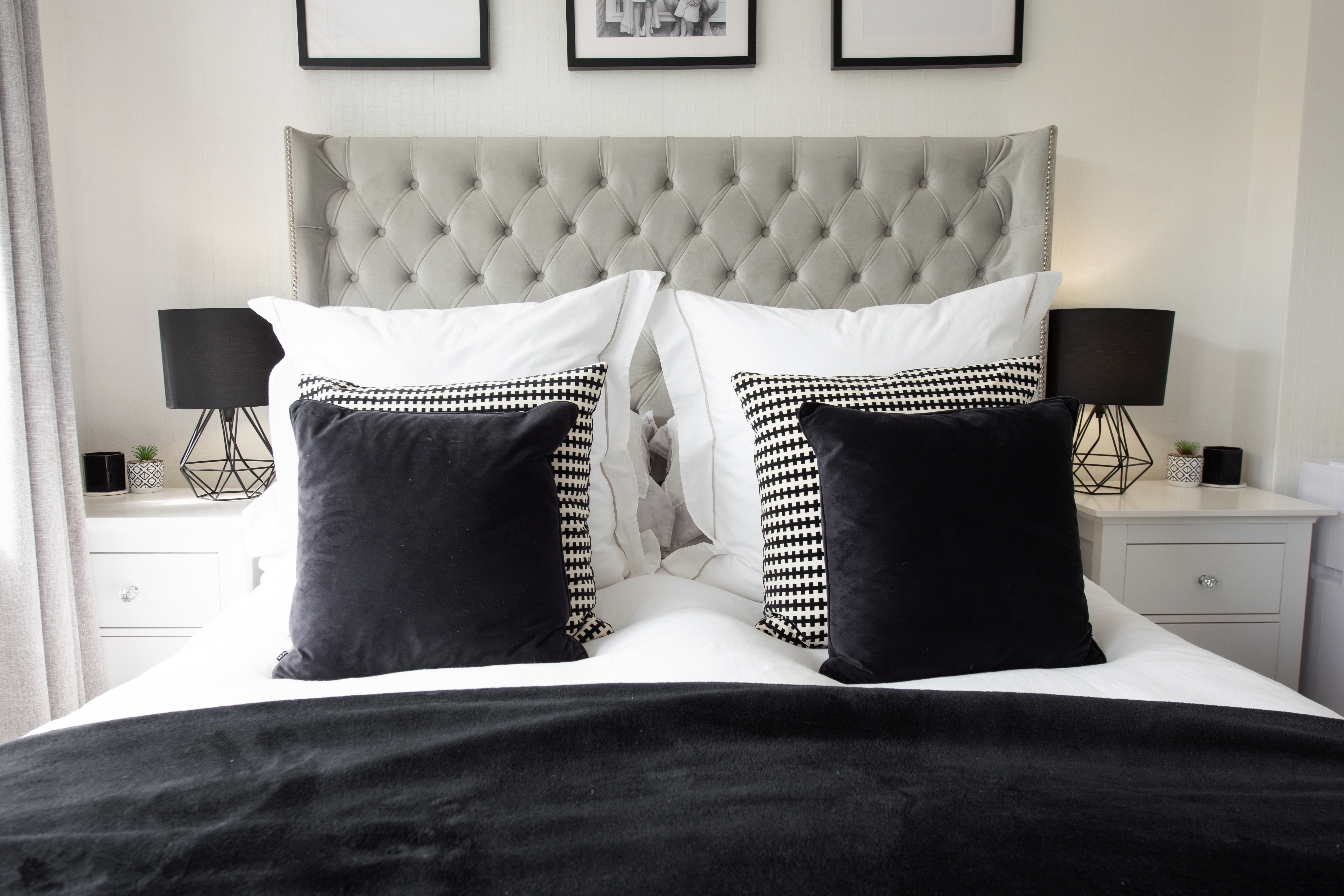 Stylish bedroom with a tufted headboard, geometric lamps, and pillows arranged neatly on a neatly made bed