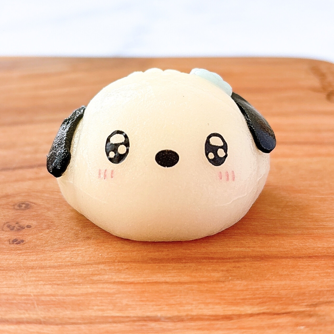 犬の形をした可愛い和菓子が木の板の上に置かれています。優しい表情が印象的です。