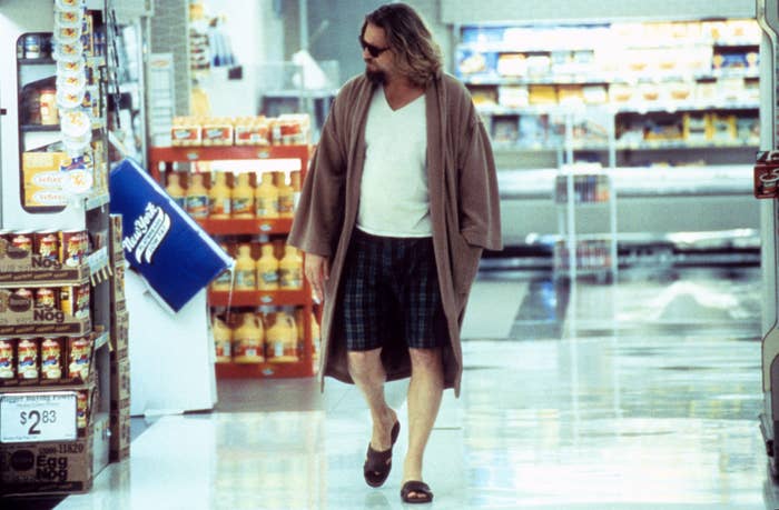 Person wearing a robe, T-shirt, shorts, and sandals walks through a grocery store aisle