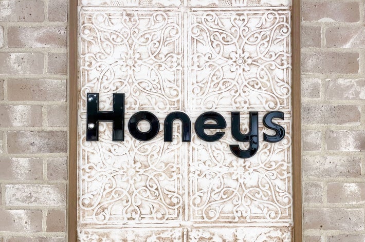 装飾された壁に「Honeys」のロゴが表示されています。