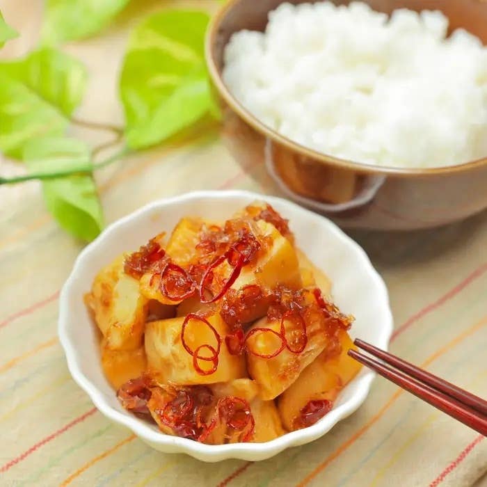 白い陶器の皿に盛られたたけのこ料理と、ご飯の入った茶碗が並んでいる。