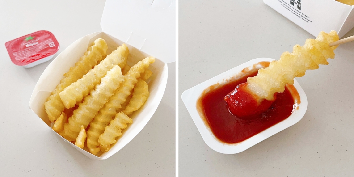 波状のフライドポテトが箱に入り、1つがケチャップに浸っています。ケチャップの小袋があります。