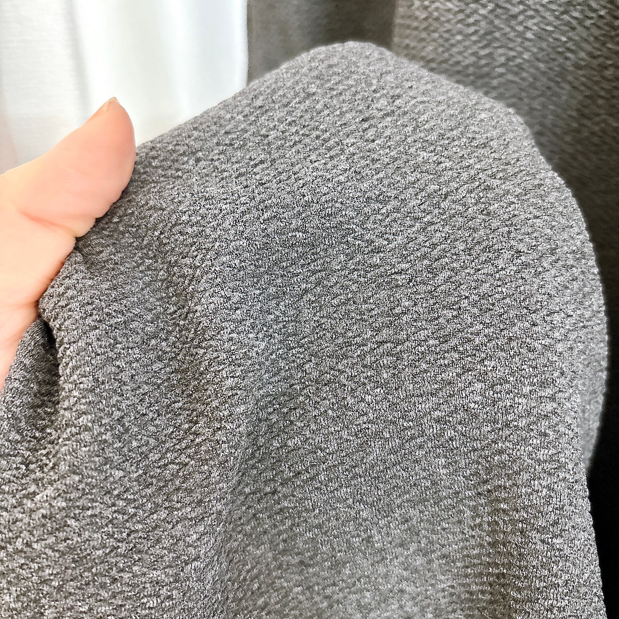 手に取った布地の近接画像。粗い織り目が見える。