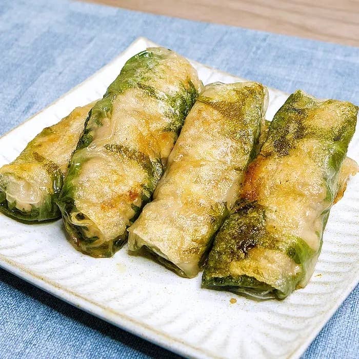 4本の野菜と肉が詰まった春巻きが白い皿に盛られている。