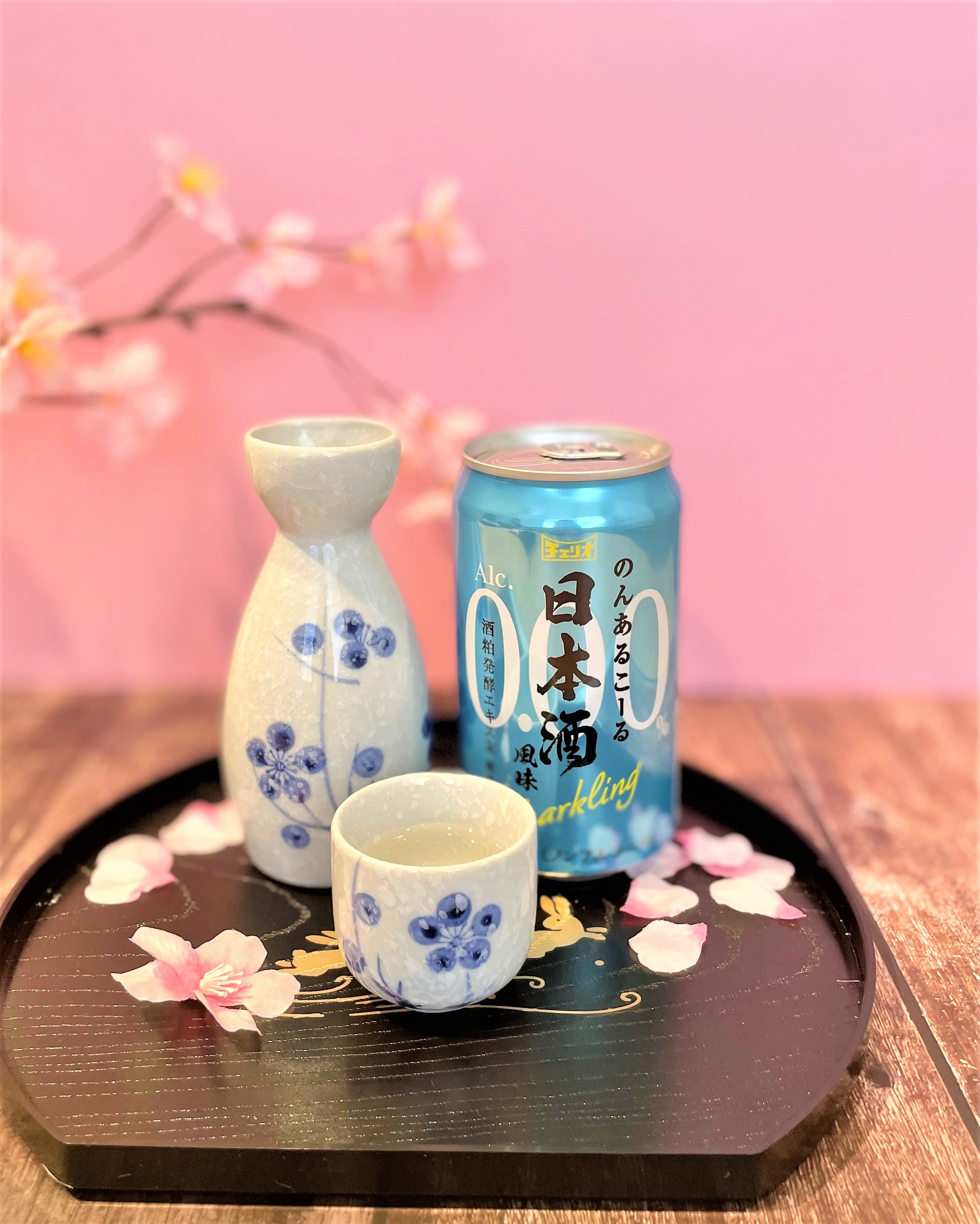 お猪口と徳利が添えられた桜装飾の中、日本酒スパークリングの缶が木のトレイに置かれている。