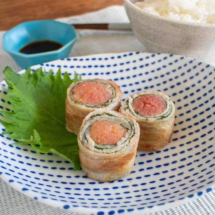 皿に盛られた3つの豚肉巻き寿司と大葉。後ろにはご飯と醤油が置かれている。