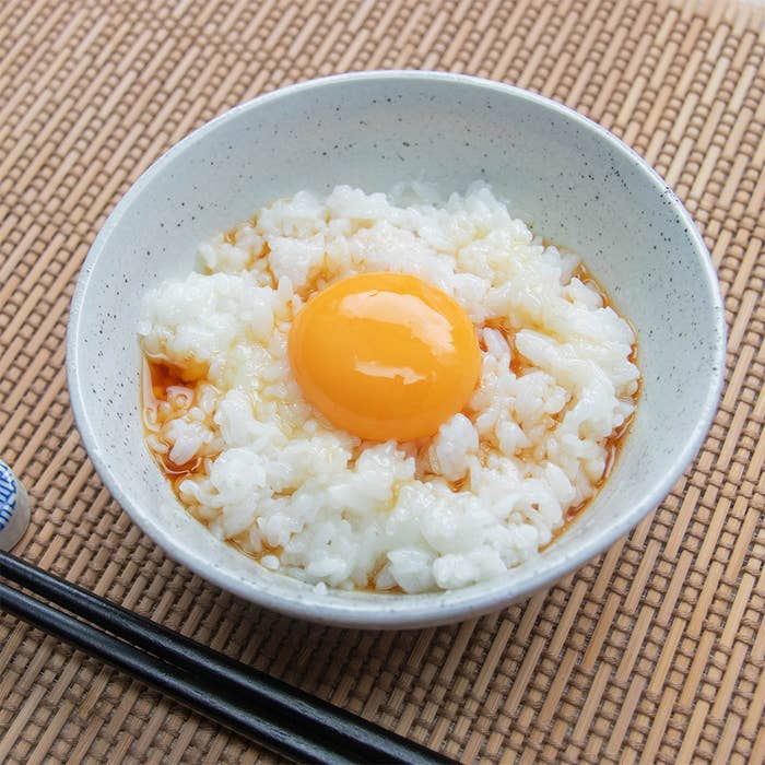 テーブルに置かれた白い茶わんに盛られている、しょうゆがかかった卵かけご飯。