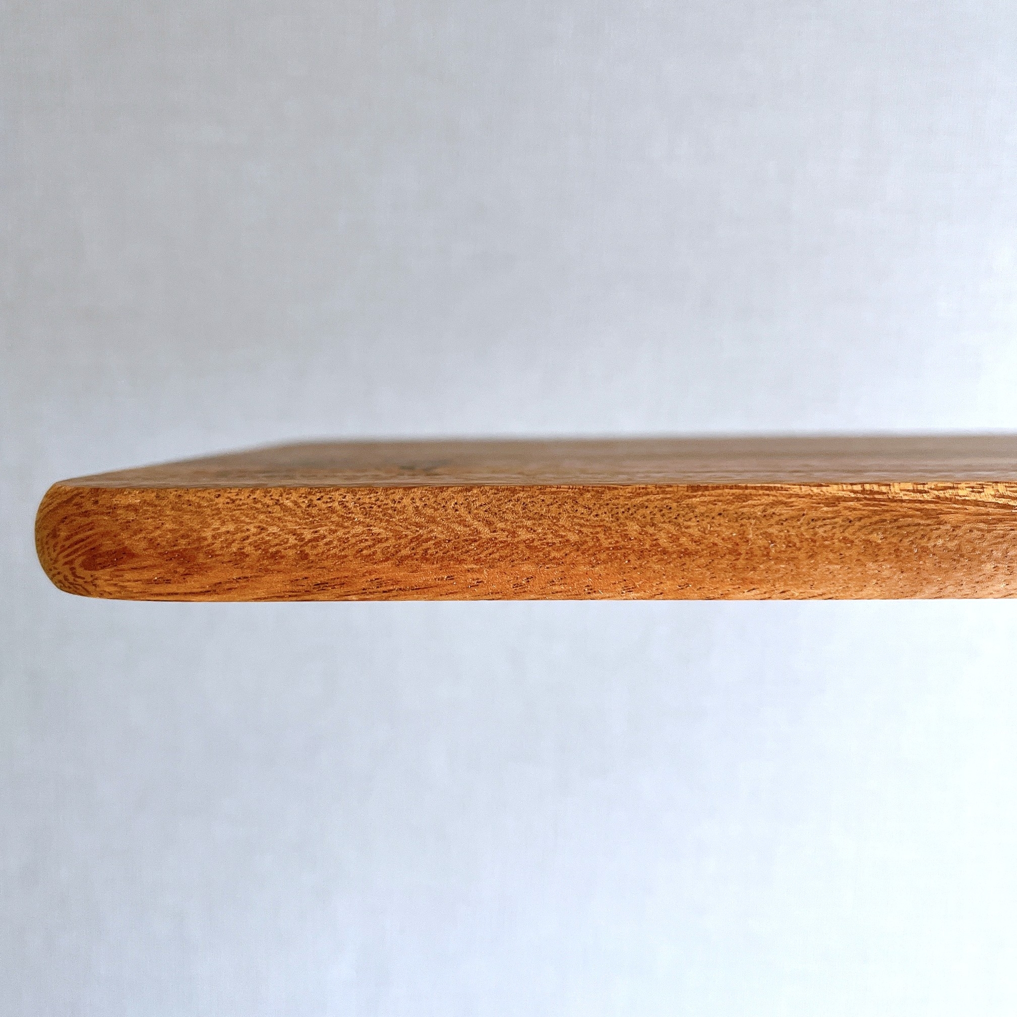 木製の棚の端が浮かんでいる様子。背景は白い壁。