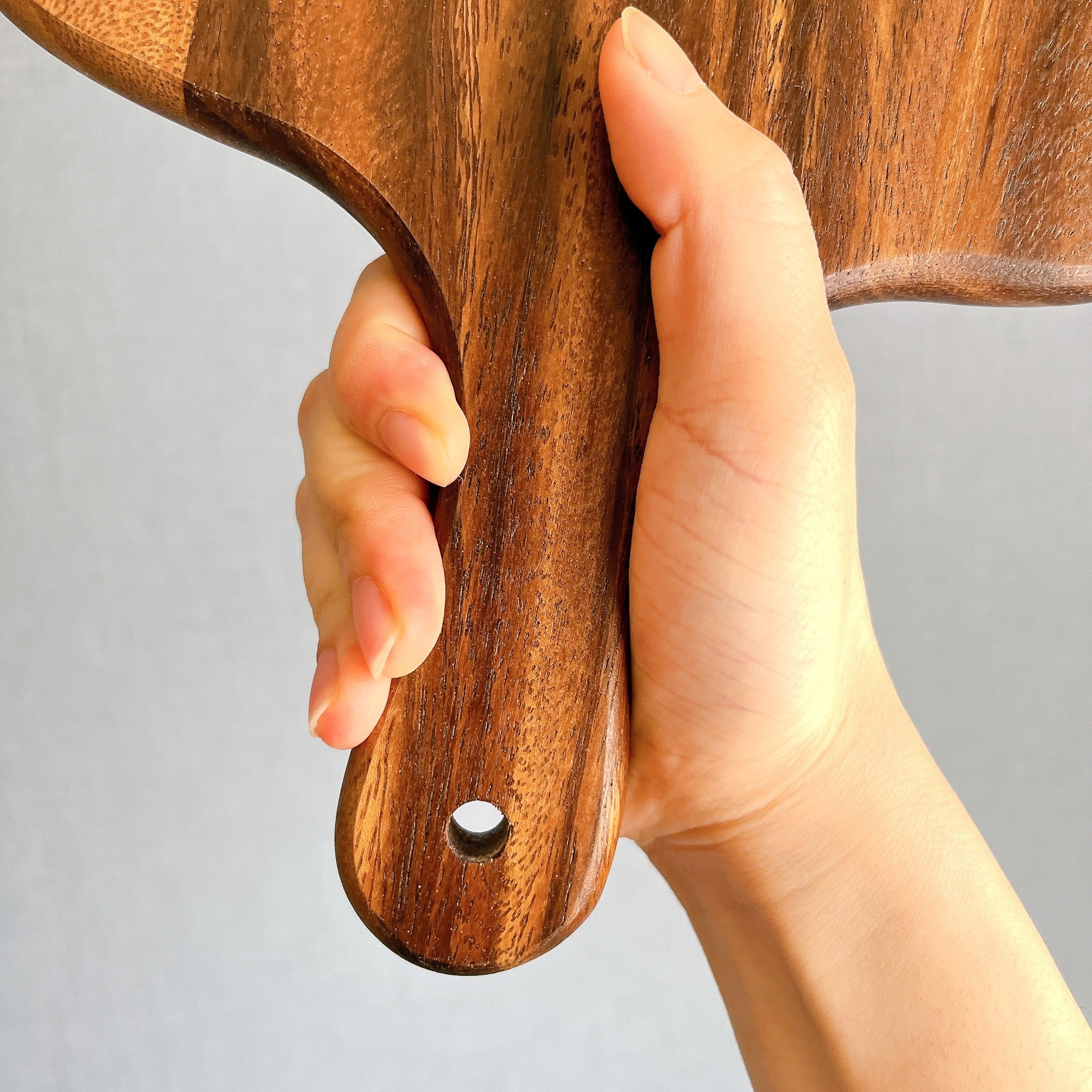 手に持たれた木製のカッティングボード。