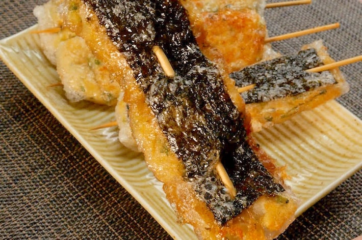皿に盛られた串焼きの天ぷら。海苔がトッピングされている。食卓の風景。