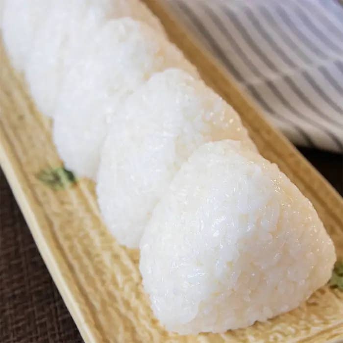 お皿に並んだ数個の三角形のおにぎり。質感が見える近接撮影。