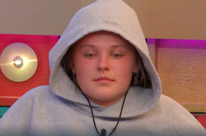 Person wearing a hoodie, seated indoors with a neutral expression, featured in a celebrity-focused article