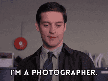 A person in a button-up shirt and suit jacket with text overlay: "I'm a photographer."