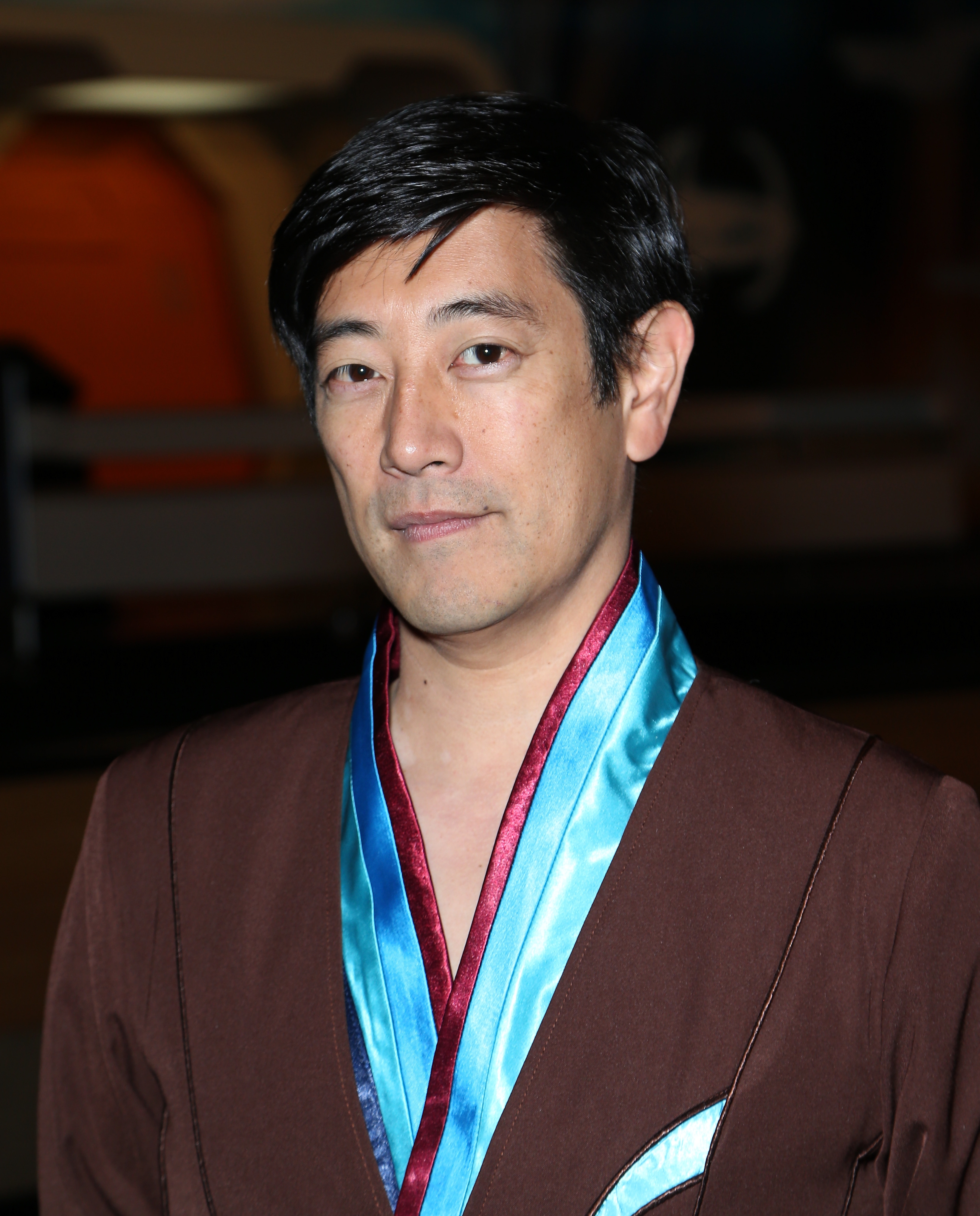 Person wearing a brown suit with a satin lined collar