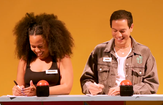 Two people with name tags, Sandra and Ivan, smile and write on paper behind buzzers, set against a simple background
