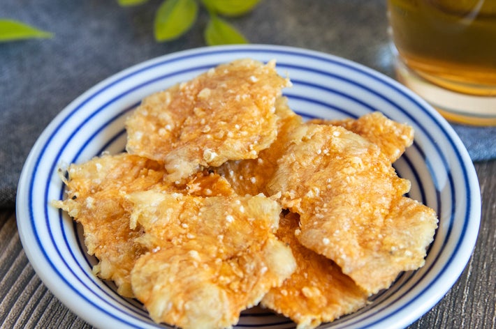 お皿に盛られたクリスピーなチキンスナックと飲み物が並んでいる。背景に植物が見える。