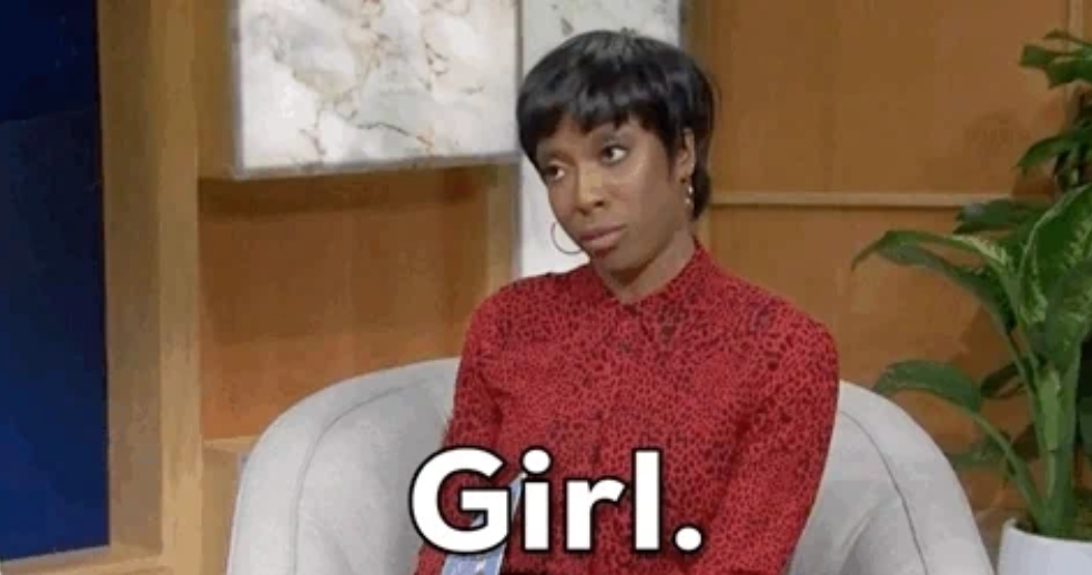 Person on a talk show set, wearing a patterned blouse, making an expressive look. Text overlay: "Girl."